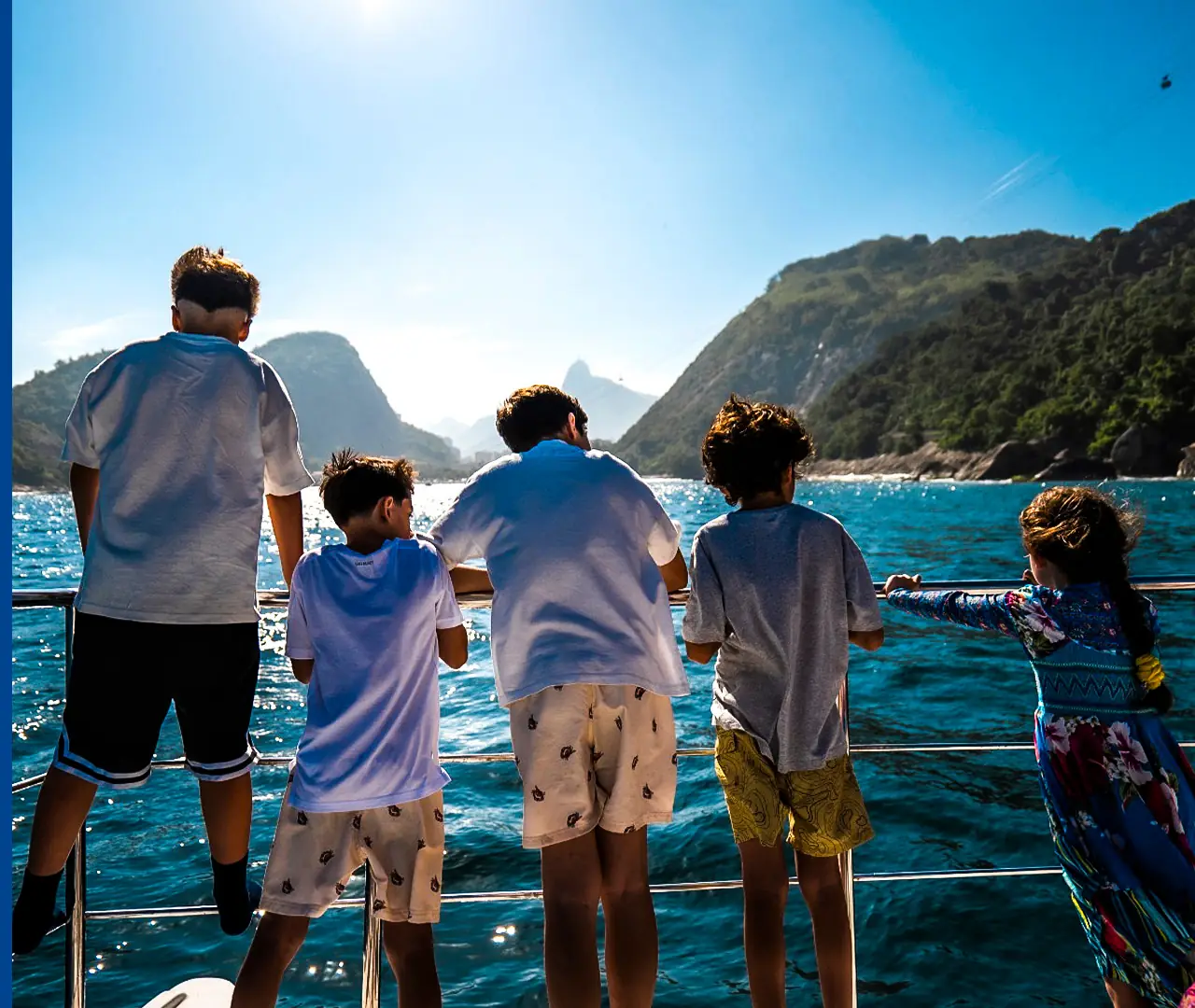 Children on a yacht’s bow looking at the sea and mountains
