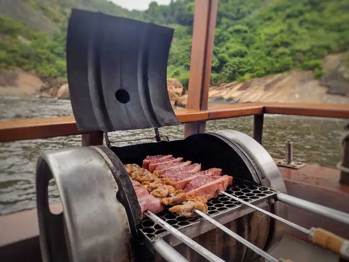 Churrasqueira a bordo com espetos de carne e linguiça